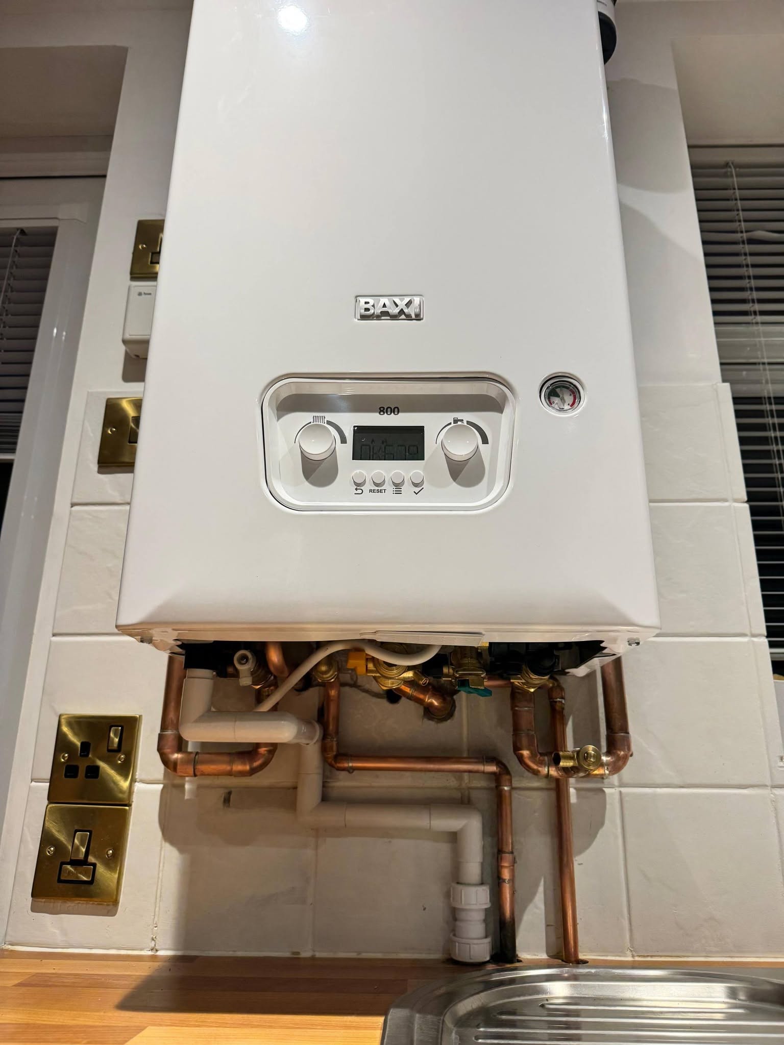 A Baxi combi boiler with its cover off showing new copper pipework underneath