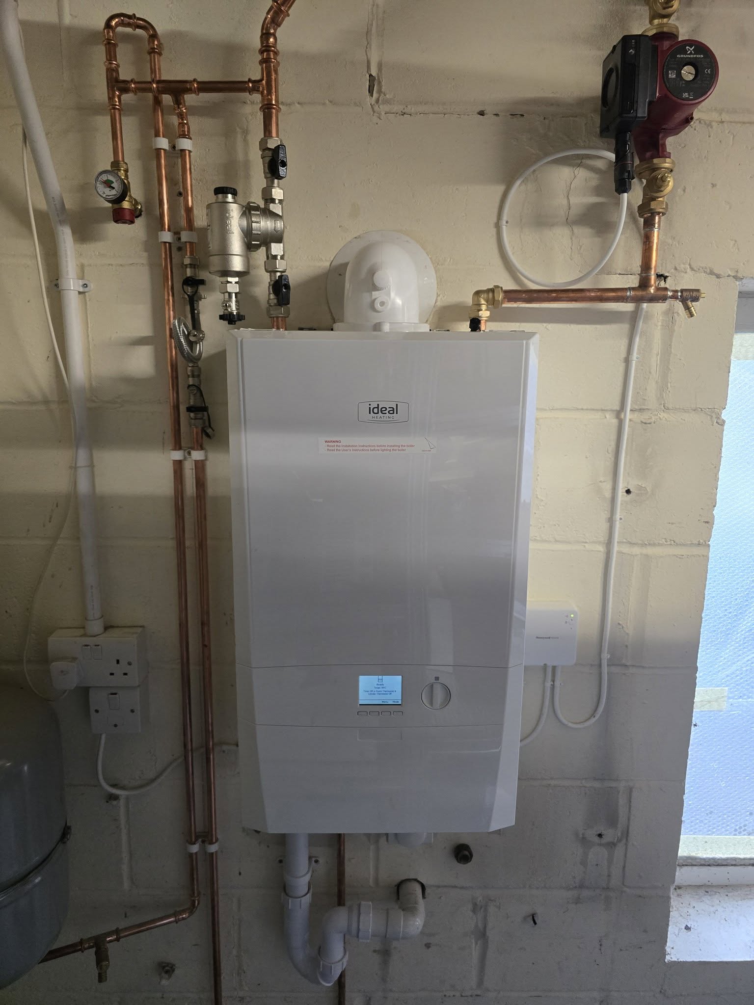 A new Ideal wall-hung boiler in a garage with pump and copper pipework