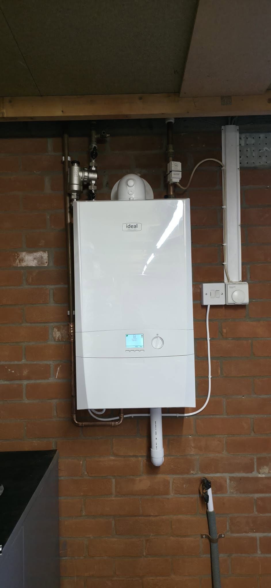 A white wall-hung boiler mounted on a brick wall