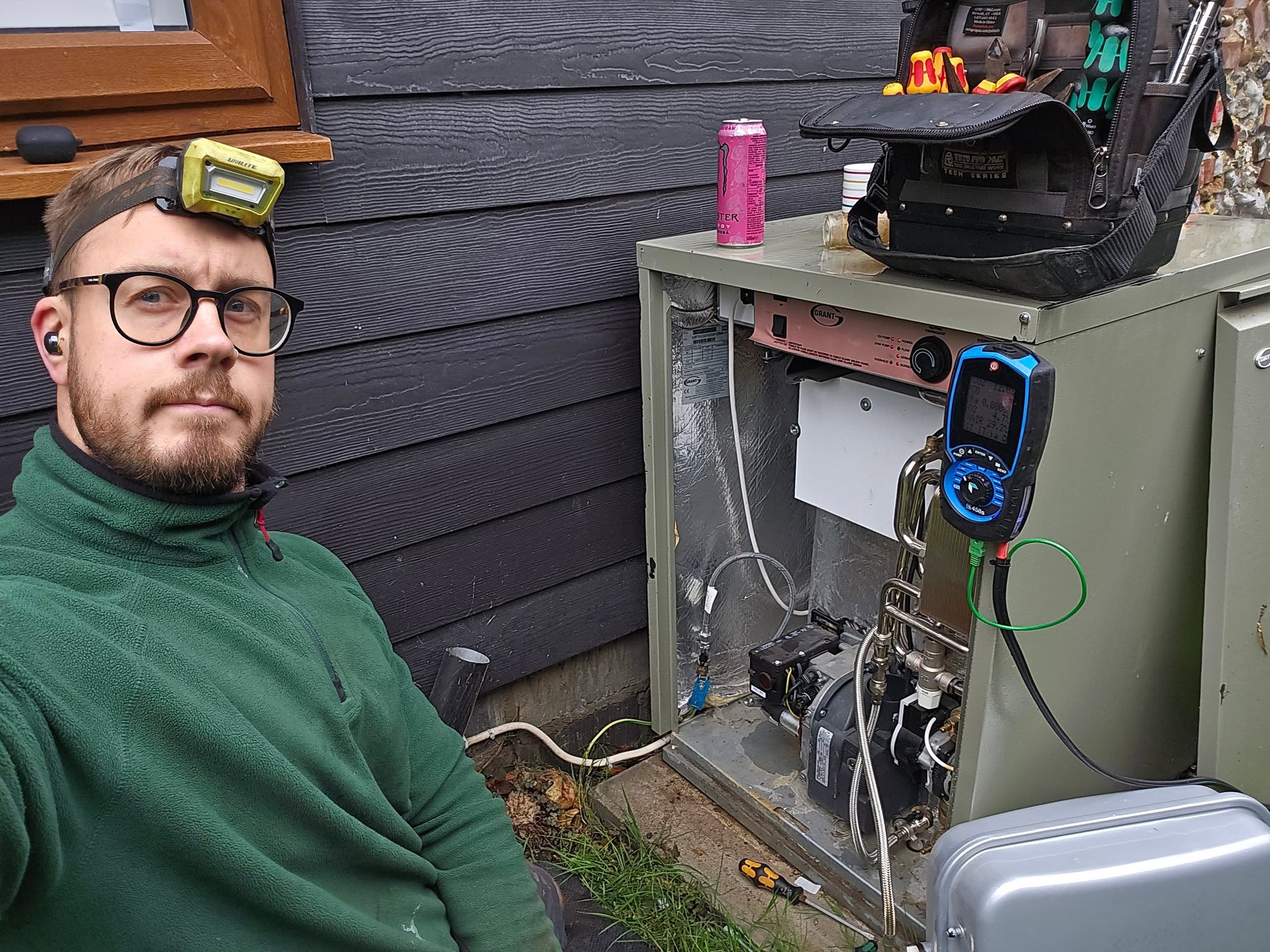 Our engineer beside an outdoor boiler under service with a flue gas analyser connected