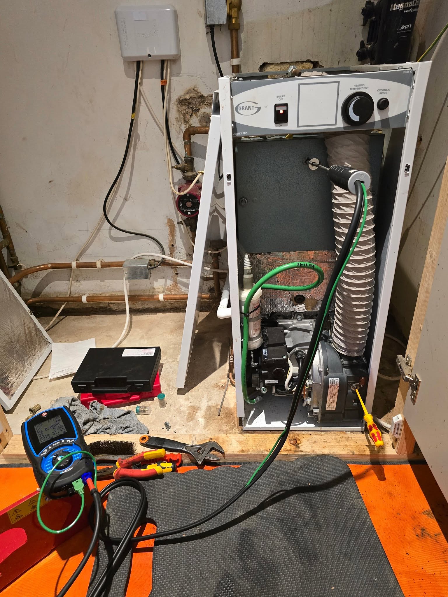 A floor-standing boiler opened up with test equipment on the floor