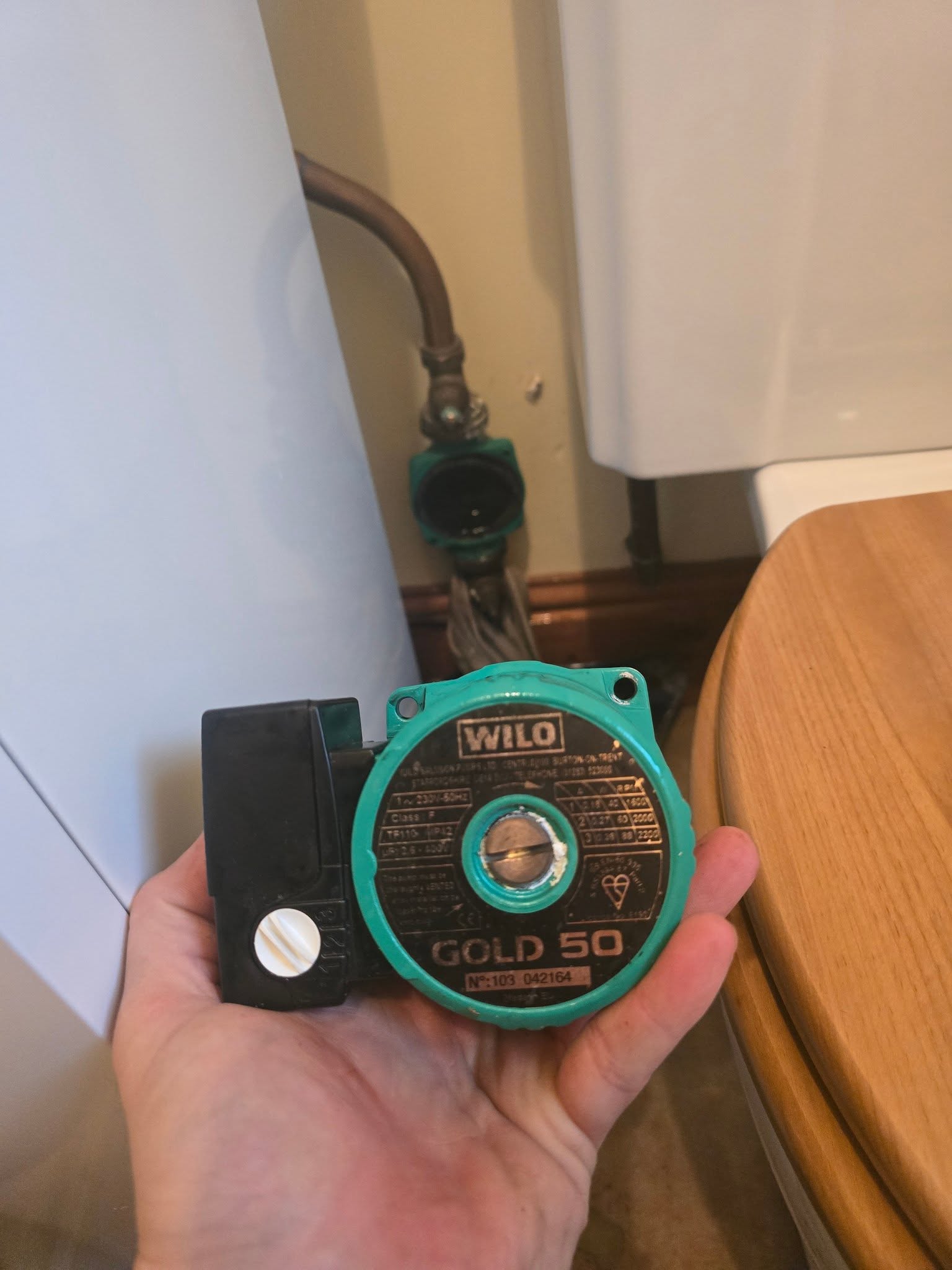 A hand holding an old circulating pump removed from a heating system