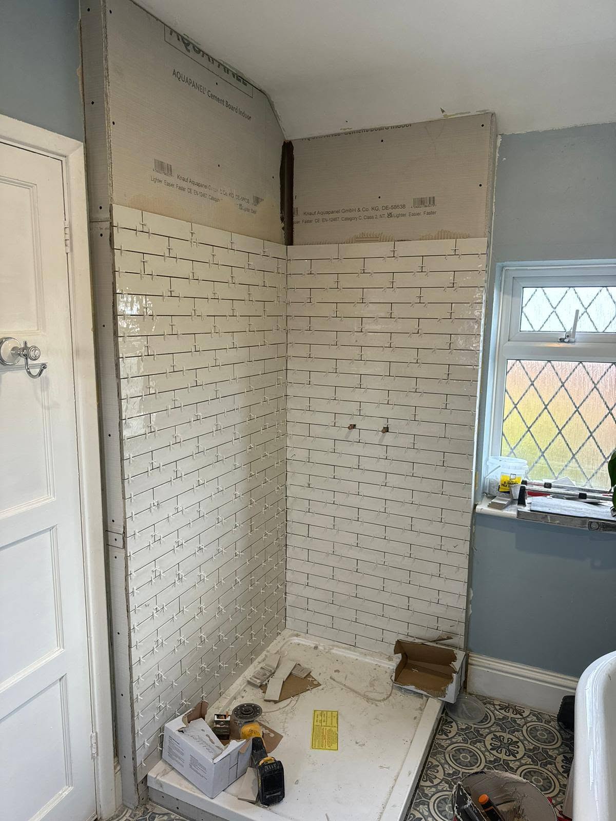Tiling: White brick-style tiles going on above the new tray.