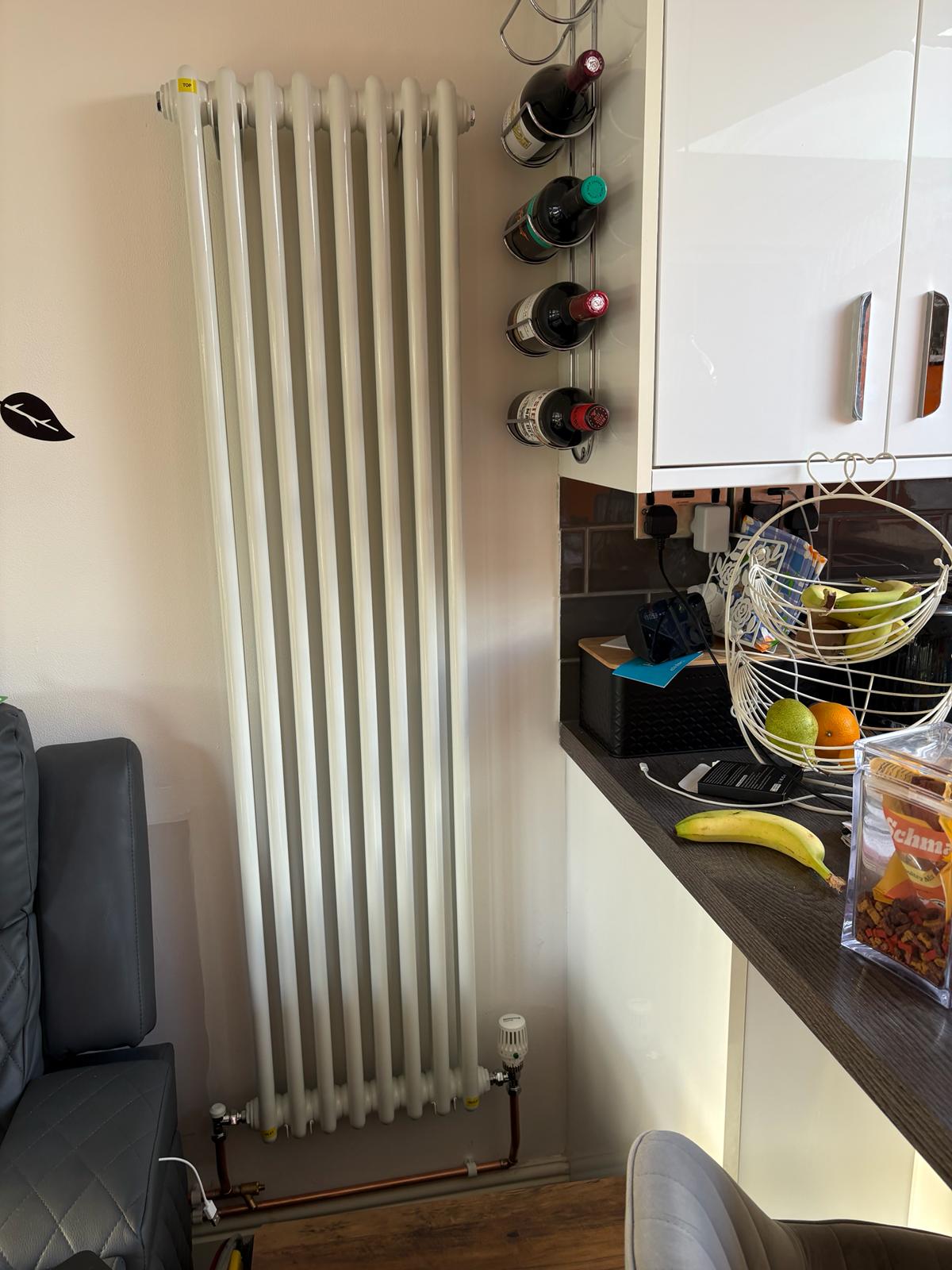 A tall white column radiator in a kitchen diner