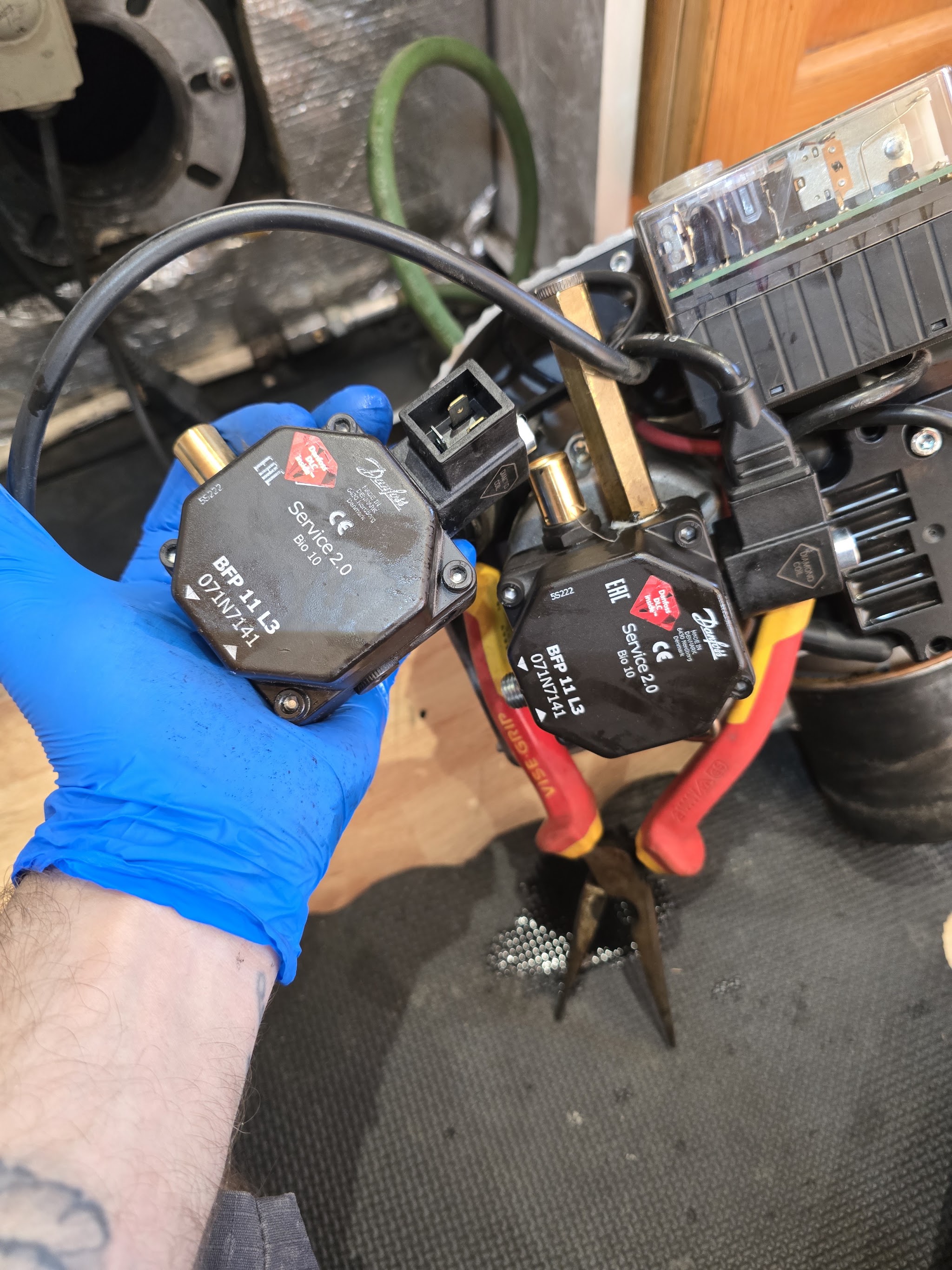 A gloved hand holding two burner fuel pumps